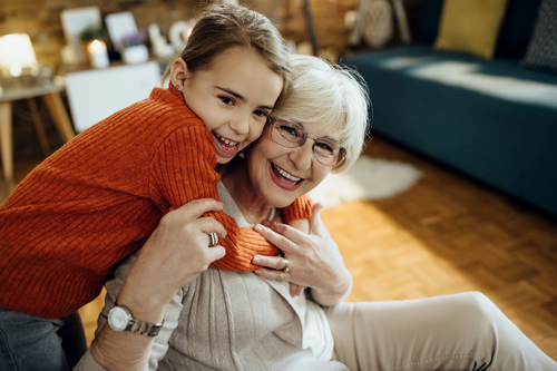 Happy little girl having fun while embracing her grandmother at home.
